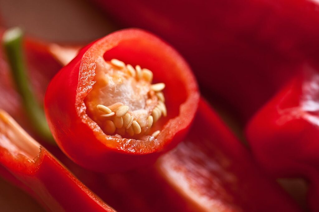 Macro photograph of sliced red chili peppers showing seeds and vibrant colors.